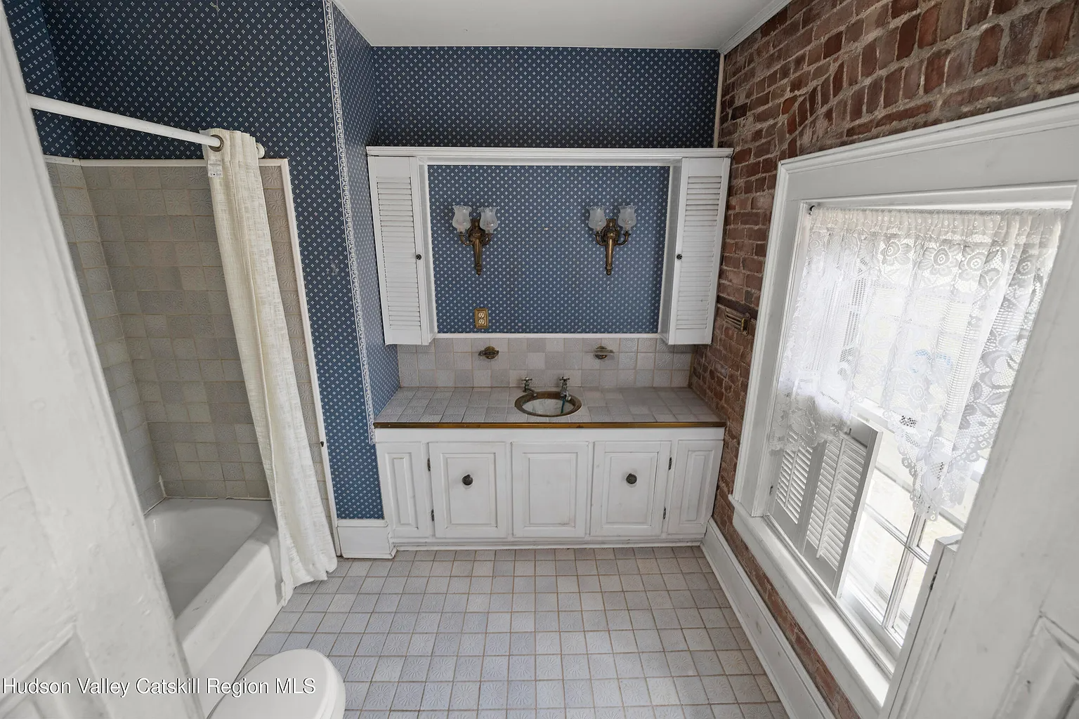 bathroom with blue wallpaper, exposed brick