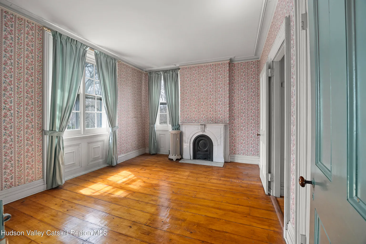 bedroom with pink floral wallpaper, marble mantel