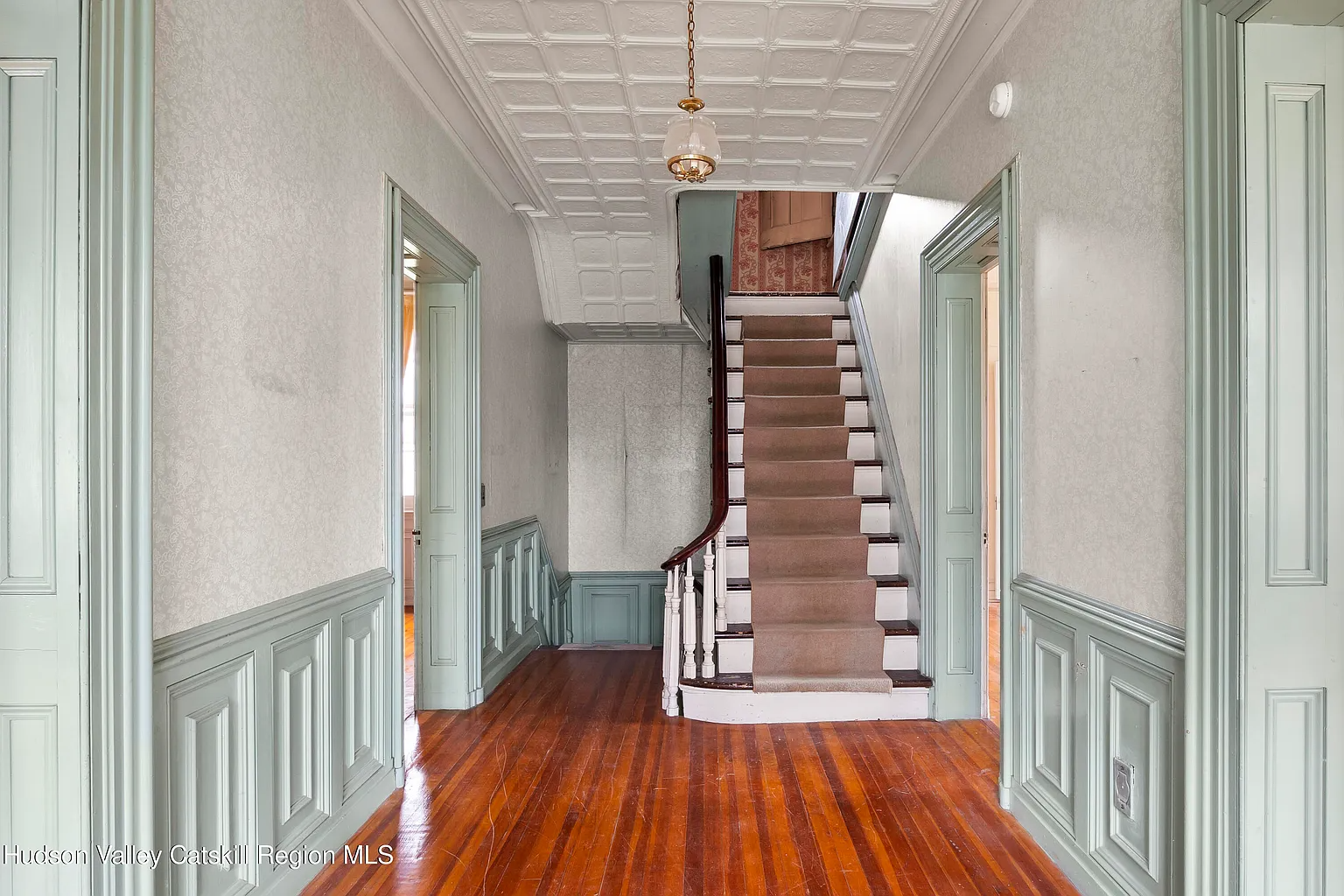 hall with green painted woodwork, tin ceiling