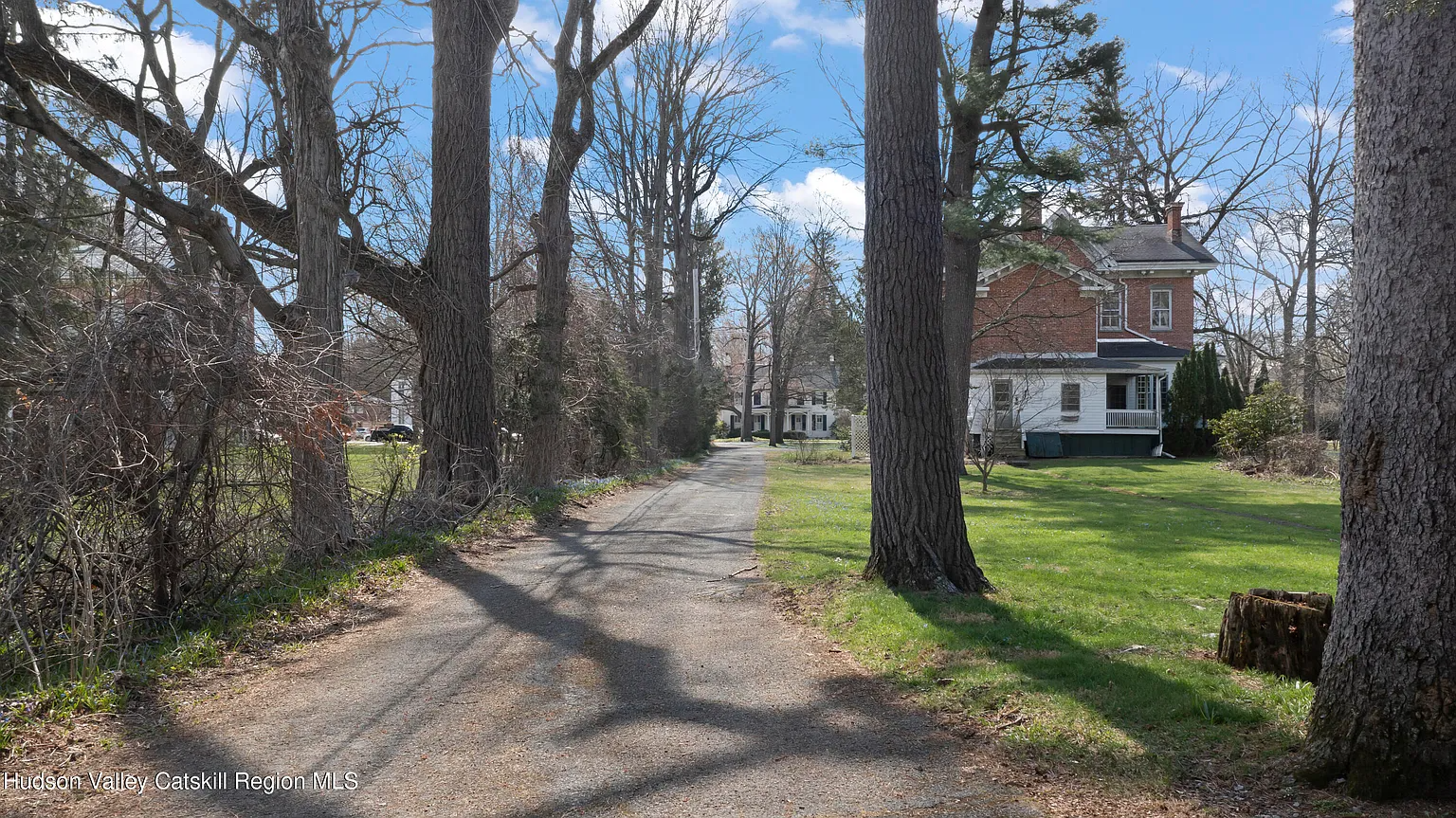 driveway with view of rear facade of brick house