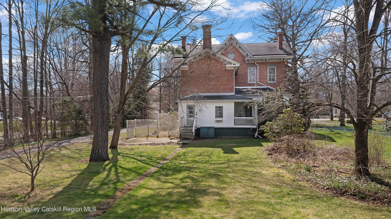 rear facade of a brick house with a yard and large trees
