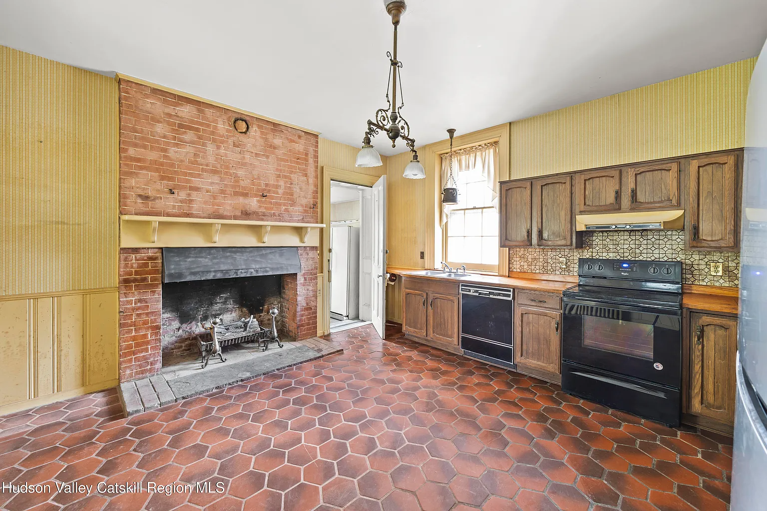 kitchen with large brick fireplace, 1970s cabinets, orange Formica counters