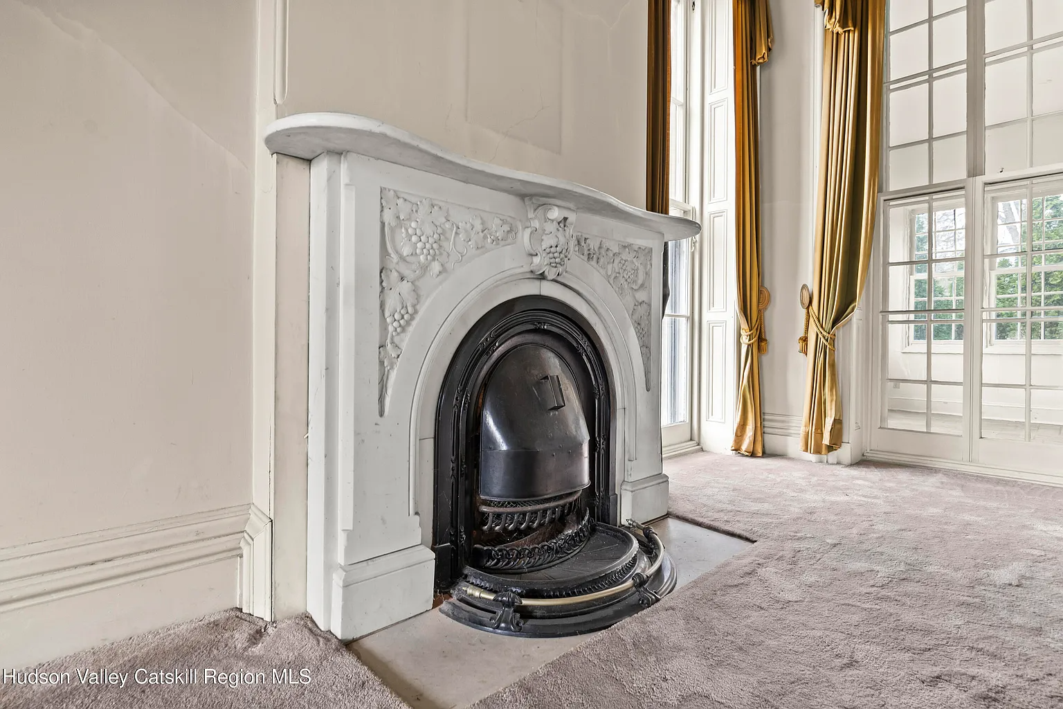 marble mantel in a parlor with wall-to-wall carpet