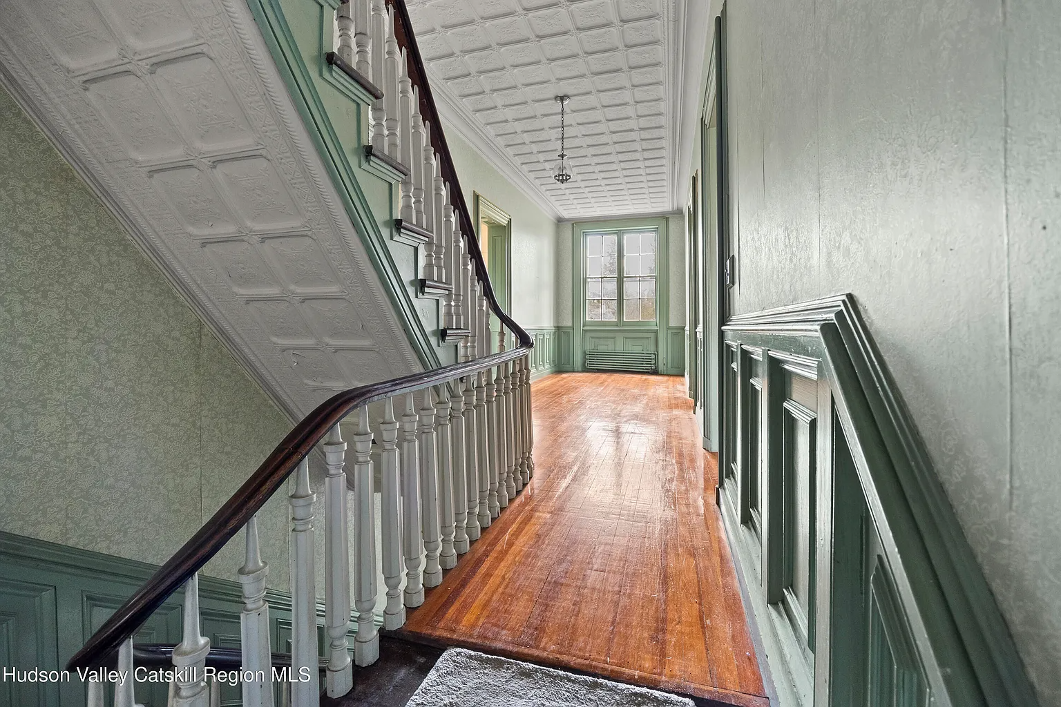 hallway with green-painted wainscoting, tin ceiling