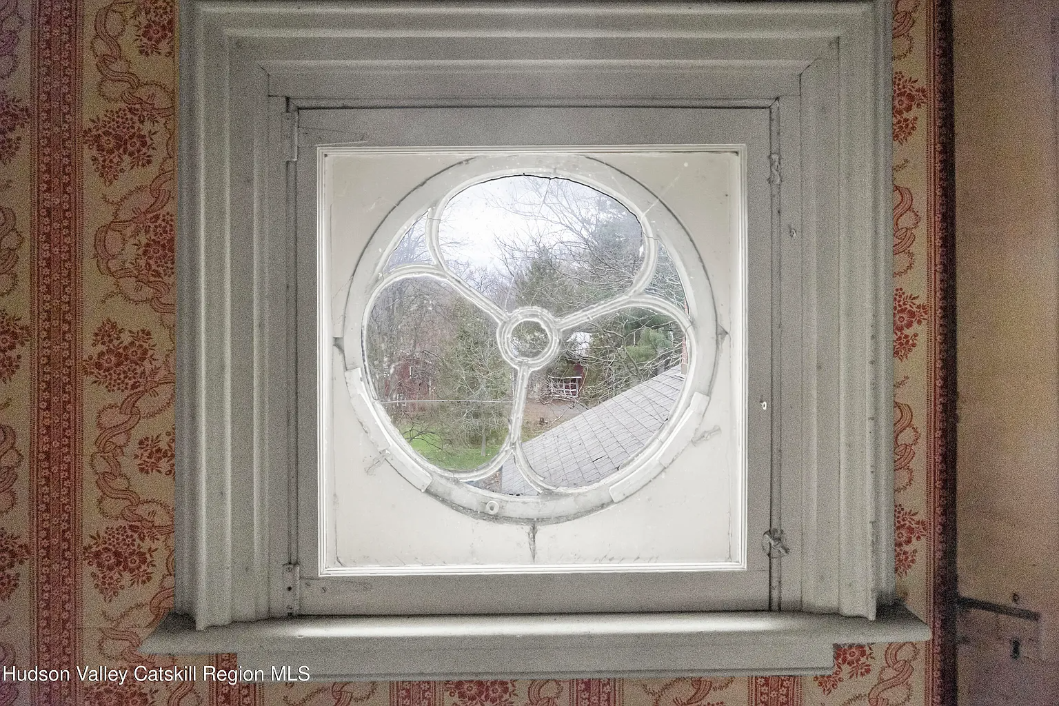 bullseye window in a room with floral and striped wallpaper