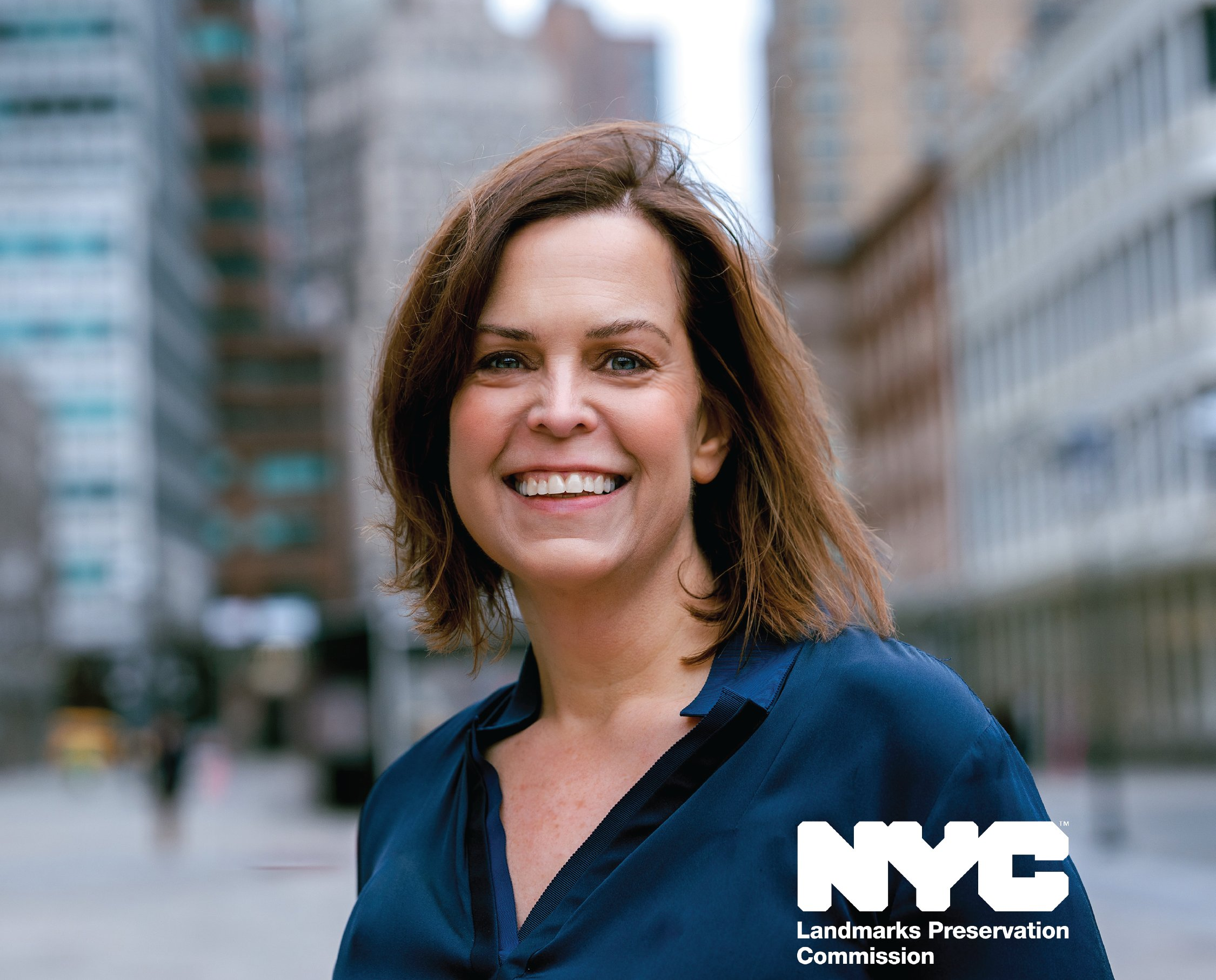 person posing outside with buildings behind