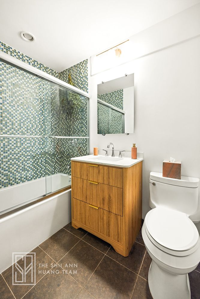 bathroom with tub, wood vanity, green and white wall tiles