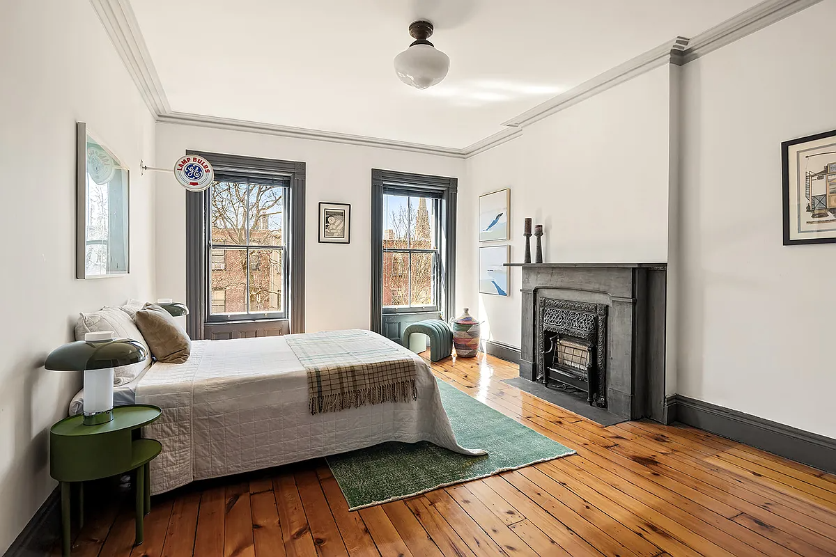 bedroom with wood floor, stone mantel, two windows