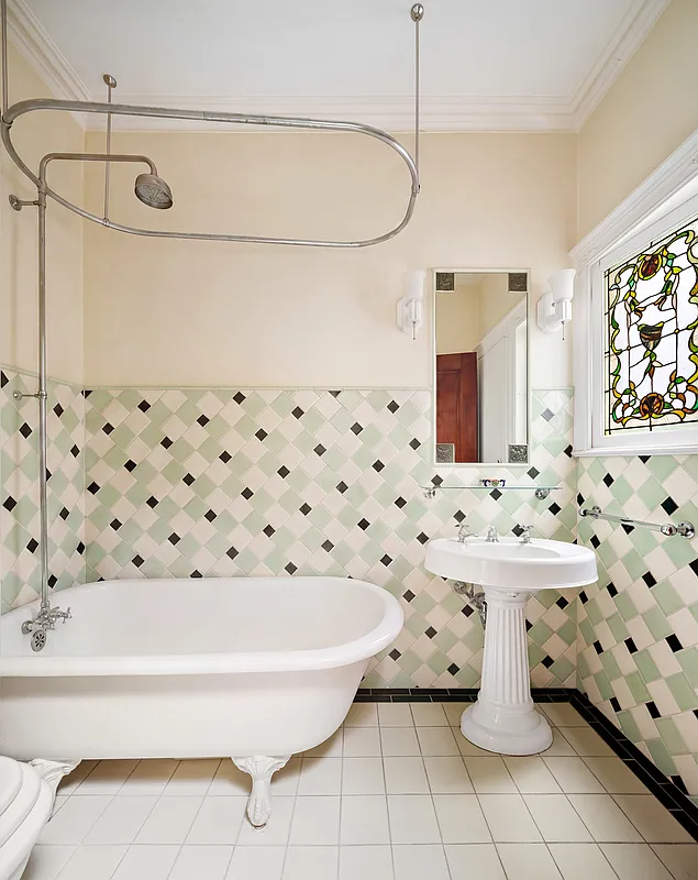 bathroom with green, white and black tile on walls, claw foot tub