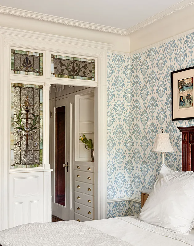 bedroom with blue and white wallpaper and glimpse of a pass-through