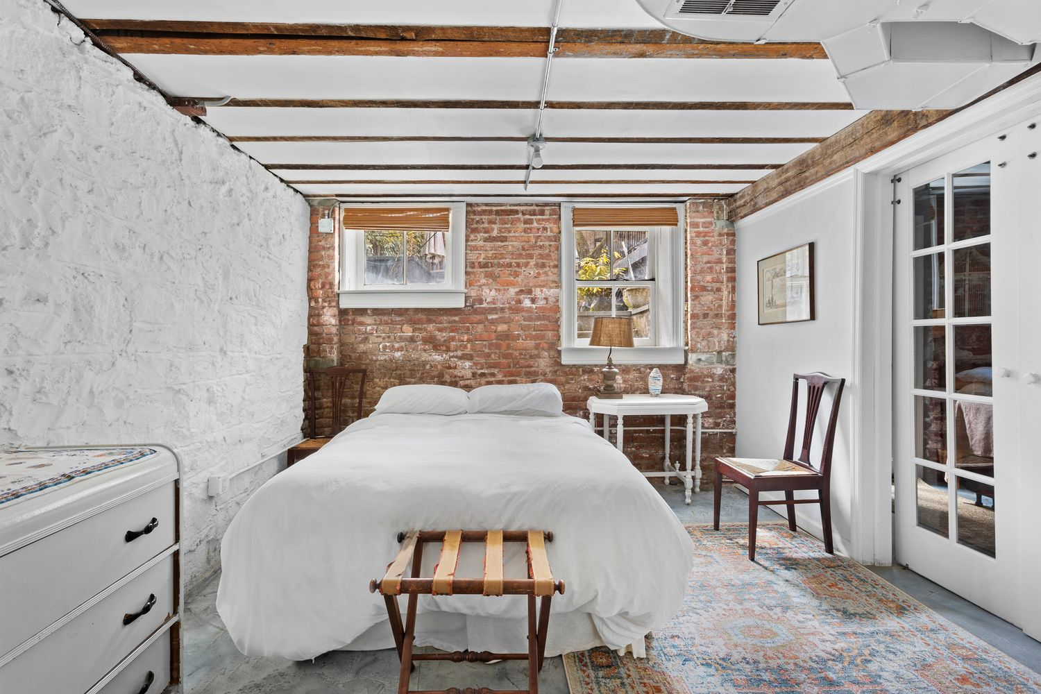 garden level bedroom with exposed brick wall, two windows