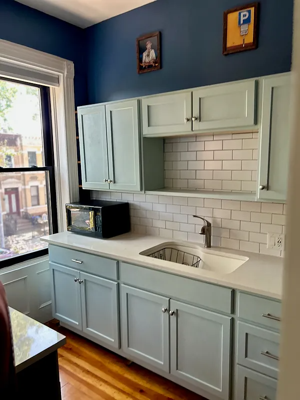 kitchen with pale blue cabinets, blue walls, white counters