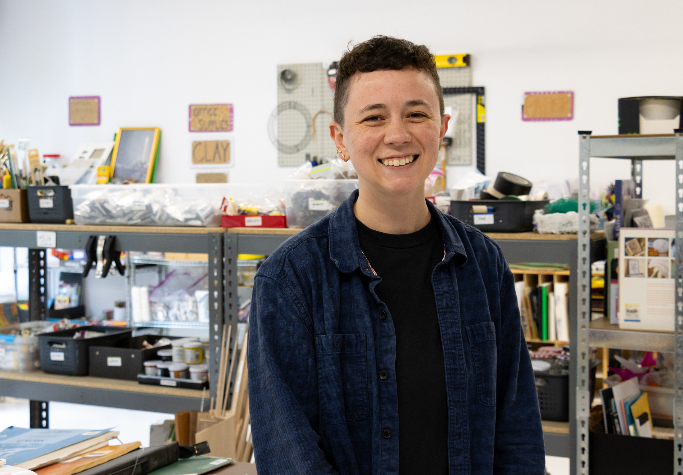 person posing in front of shelves with art and craft supplies