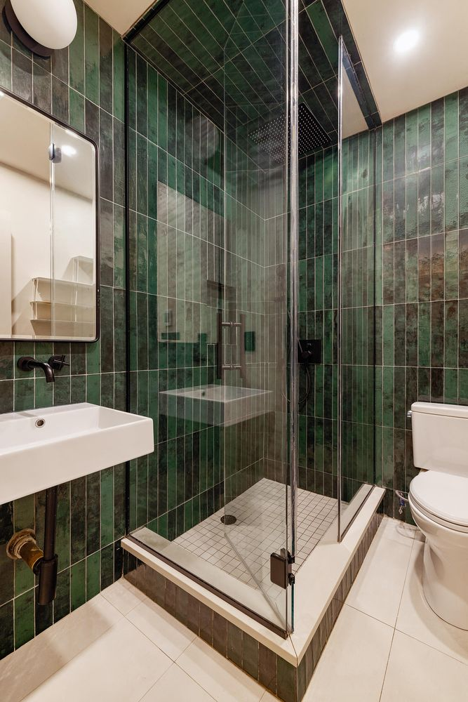bathroom with green wall tile, large glass shower