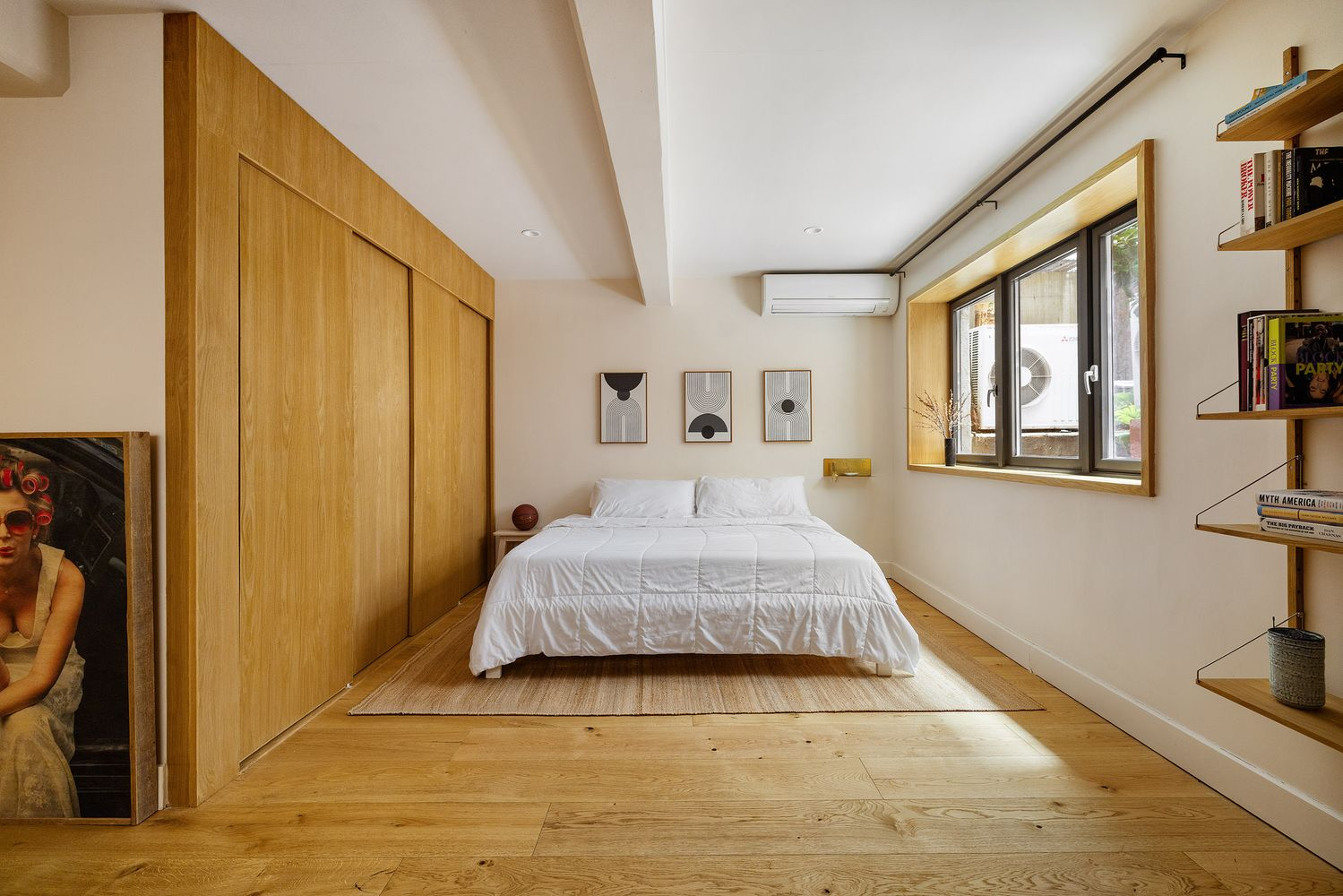 a bedroom with wide planked floorboards, wall of storage