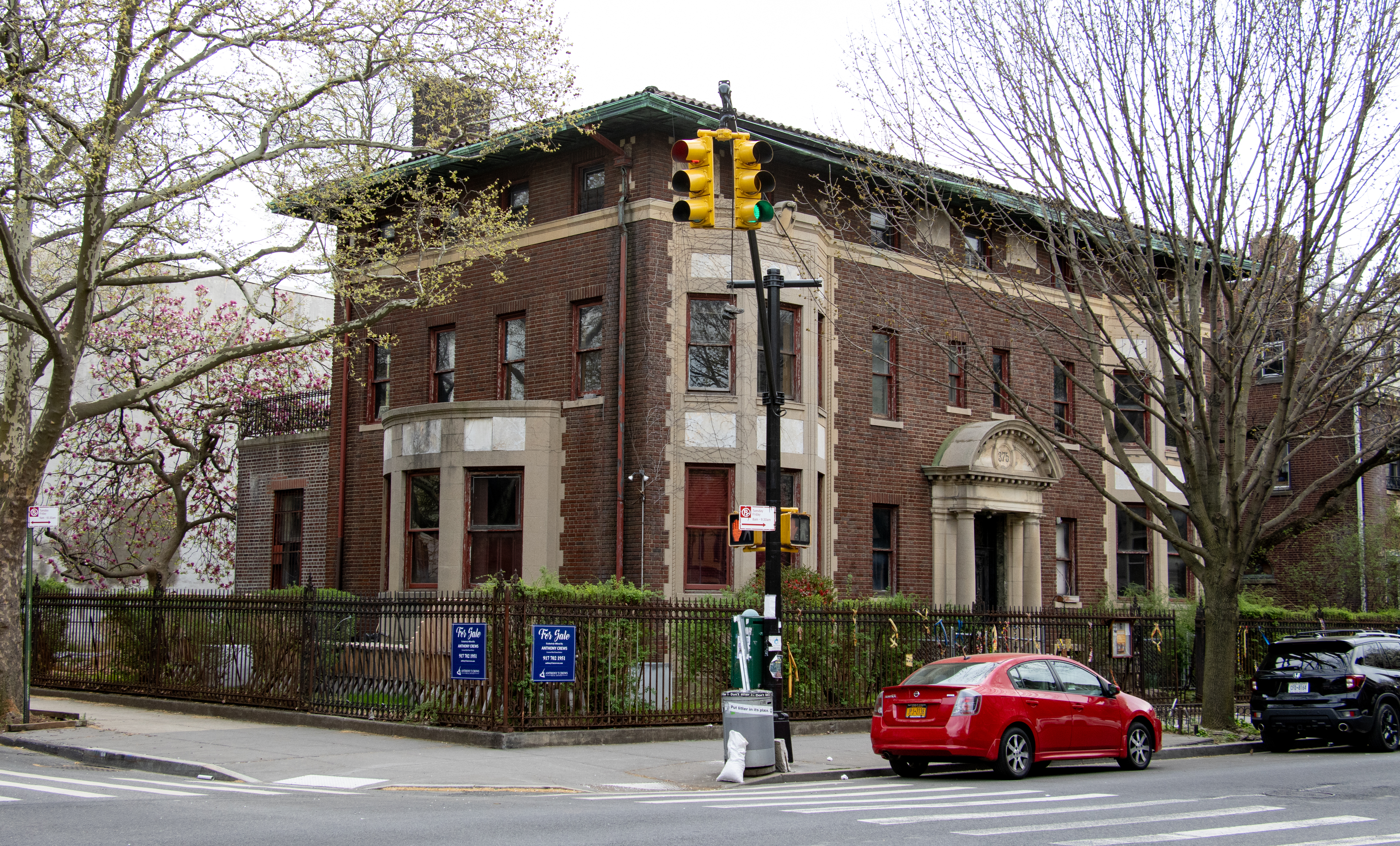 brick mansion with a for sale sign