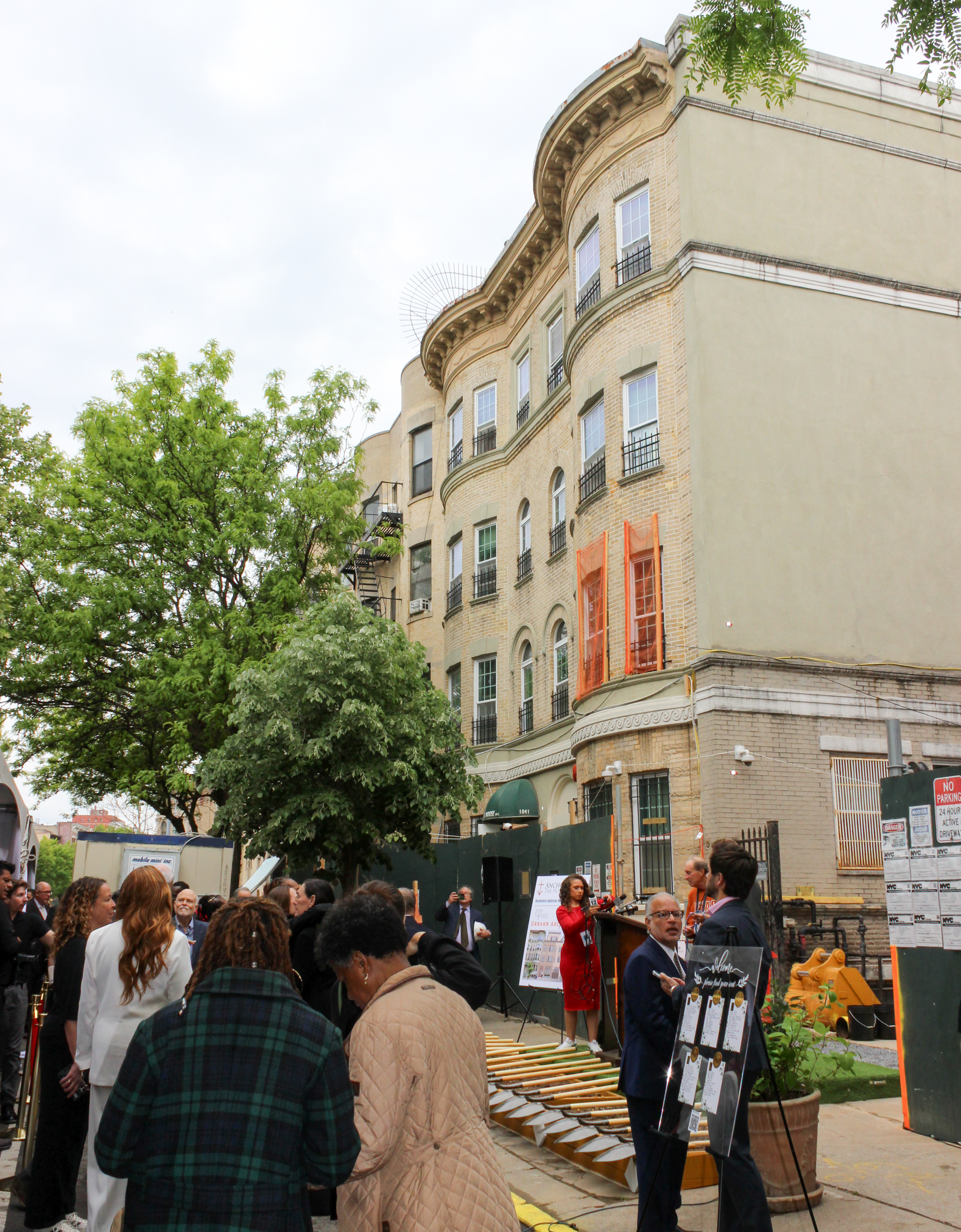 people standing in street and on sidewalk outside of a brick row house