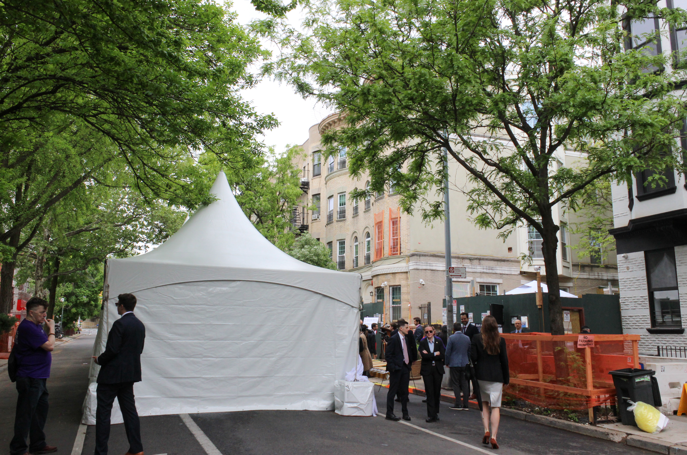 tent set up on the street outside of a brick row house and parking lot