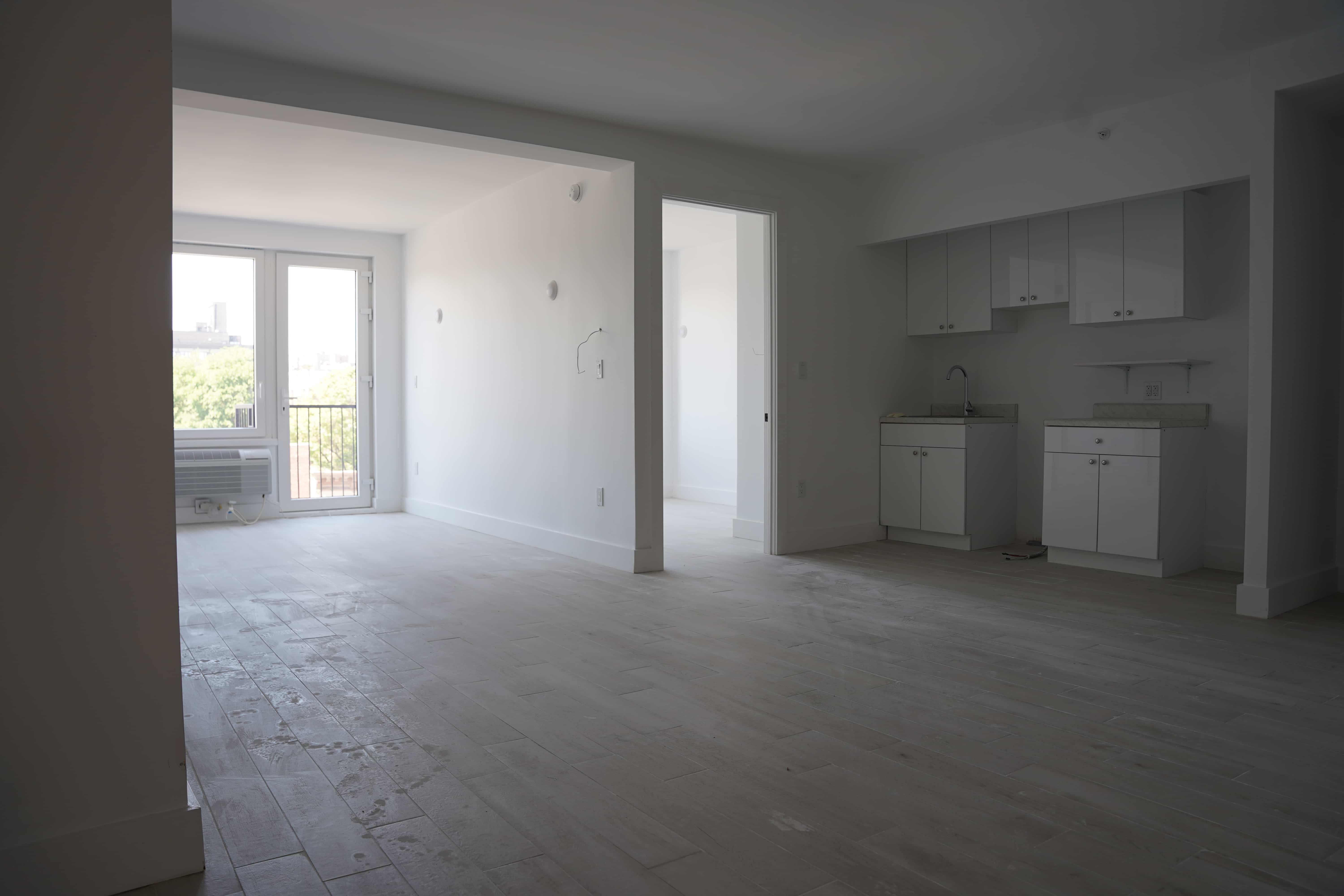 view of an apartment with large windows and a kitchen with white cabinets